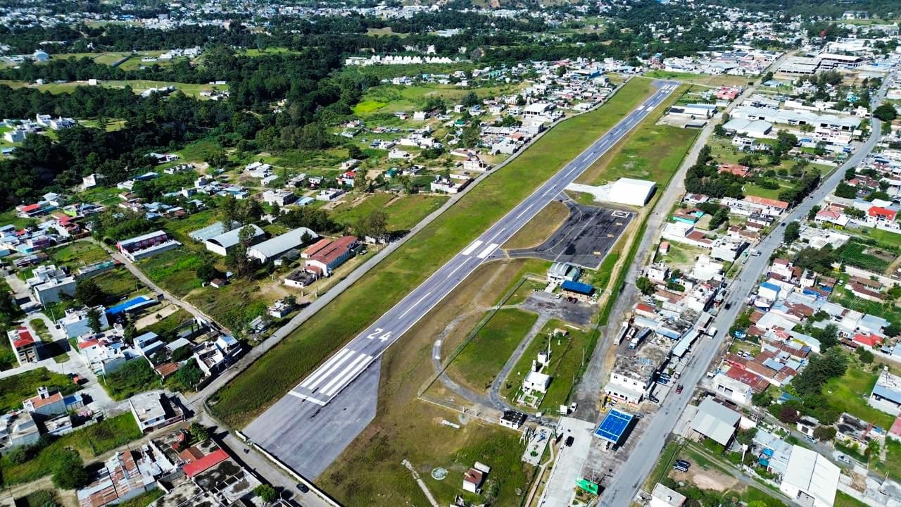 Una pista de aterrizaje asfaltada se extiende hacia un valle rodeado por montañas bajo un cielo despejado, en Huehuetenango, Guatemala (CIV Guatemala)