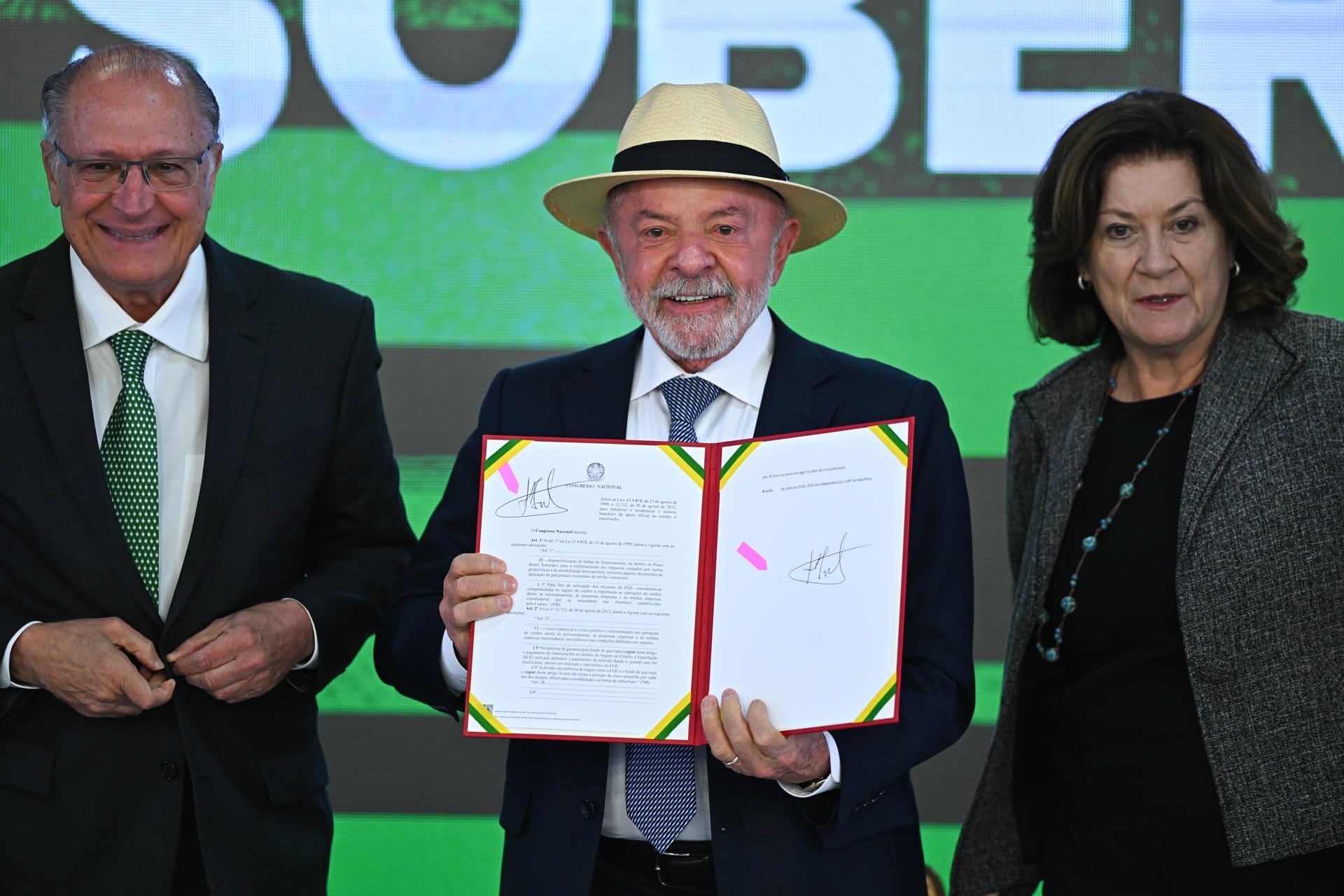 El presidente de Brasil, Luiz Inácio Lula da Silva (c), sostiene un documento junto al vicepresidente, Geraldo Alckmin (i), y de la jefa de Gabinete de la Presidencia, Miriam Belchior, durante la ceremonia de sanción del Proyecto de Ley de Conversión, que asigna recursos a las líneas de crédito del programa 'Brasil Soberano' en apoyo de las empresas afectadas por los aranceles comerciales de Estados Unidos, este miércoles en el Palacio del Planalto, en Brasilia (Brasil) (EFE/ Andre Borges)