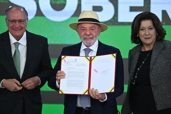 El presidente de Brasil, Luiz Inácio Lula da Silva (c), sostiene un documento junto al vicepresidente, Geraldo Alckmin (i), y de la jefa de Gabinete de la Presidencia, Miriam Belchior, durante la ceremonia de sanción del Proyecto de Ley de Conversión, que asigna recursos a las líneas de crédito del programa 'Brasil Soberano' en apoyo de las empresas afectadas por los aranceles comerciales de Estados Unidos, este miércoles en el Palacio del Planalto, en Brasilia (Brasil) (EFE/ Andre Borges)