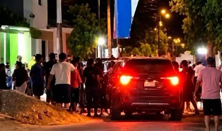 Un policía y personal del Ministerio Público revisan el interior de un automóvil rojo con las puertas abiertas durante la noche