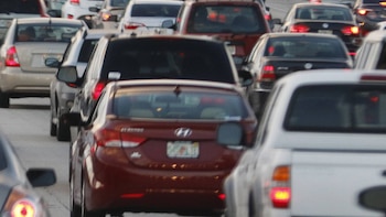 Vista trasera de una multitud de coches atascados en el tráfico denso de una autopista de varios carriles, con un camión Toyota blanco visible a la derecha