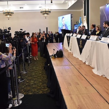 Seis autoridades en una mesa del Tribunal Supremo Electoral frente a asistentes sentados en mesas con rótulos de organizaciones políticas