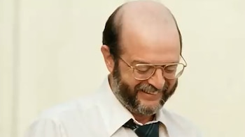 Un hombre de mediana edad con barba, gafas y calvicie parcial sonríe inclinando la cabeza