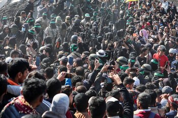 La gente se reúne mientras militantes palestinos portan rifles, el día en que entregan a los rehenes retenidos en Gaza desde el mortal ataque del 7 de octubre de 2023.