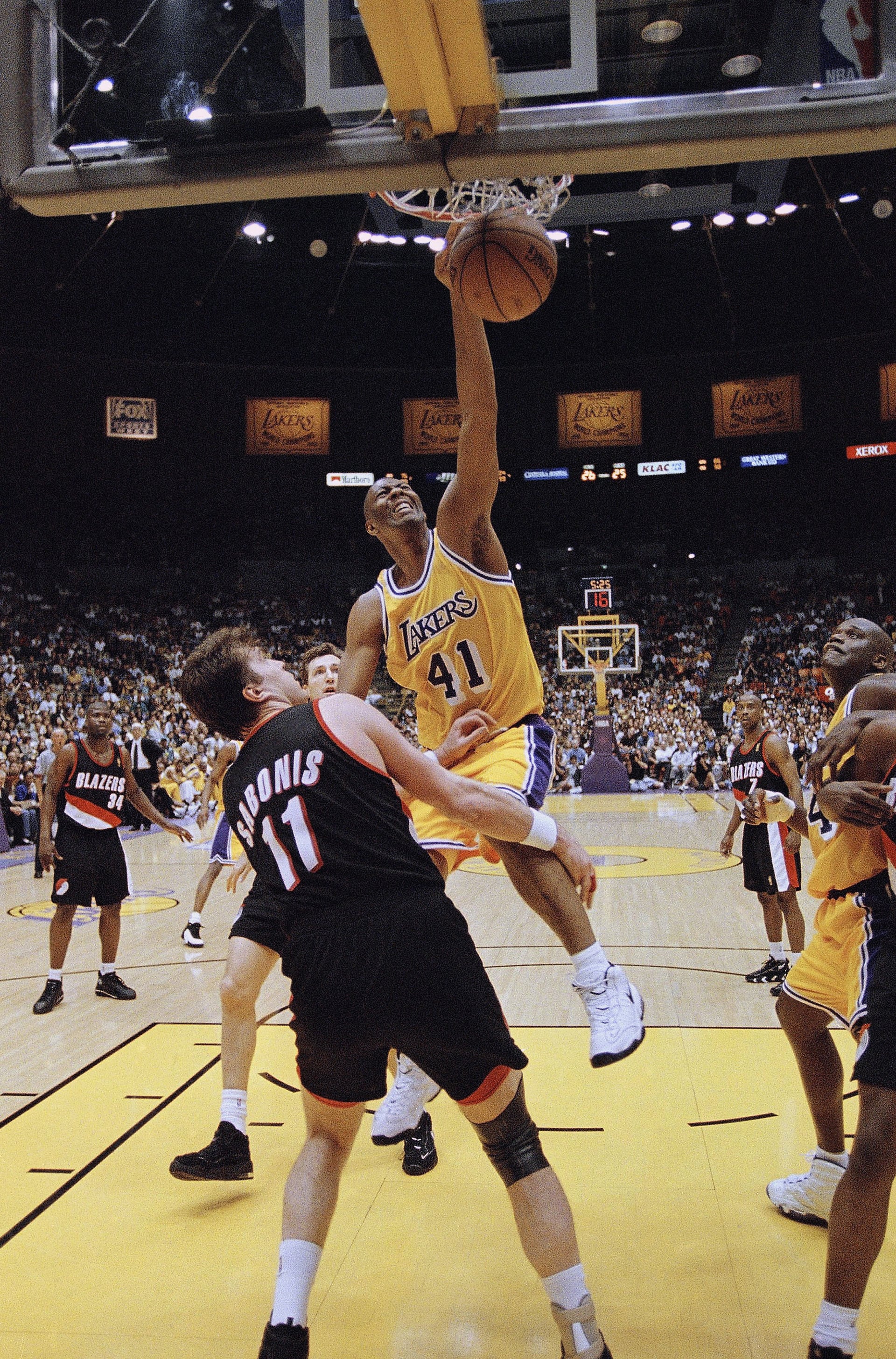 Elden Campbell con una volcada frente al lituano Arvydas Sabonis (AP Photo/Mark J. Terrill)