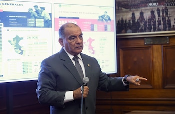El ministro César Astudillo sostiene un micrófono y señala hacia la derecha frente a dos pantallas con mapas y estadísticas de Perú