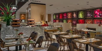 Vista interior del Market 770 Restaurant con un largo buffet de mármol lleno de pasteles, y múltiples mesas de comedor con sillas de ratán