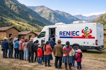 Un furgón blanco de Reniec con su logo azul y rojo estacionado en un camino de tierra. Personas forman una fila frente al vehículo en un valle montañoso con casas de adobe.