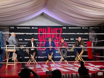 Cinco hombres sentados en sillas de director sobre un cuadrilátero de boxeo frente a una lona publicitaria con el texto Chávez