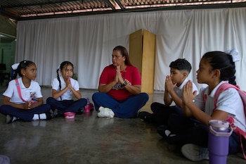 La maestra Jorli Correa dirige una oración con los pocos alumnos que pudieron regresar para el primer día de clases en la escuela UEP Simón Bolívar Fe y Alegría, tras el terremoto, en La Guaira, Venezuela. (Foto AP/Ariana Cubillos)