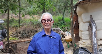La mujer con el mono azul de trabajo en el jardín de la cabaña