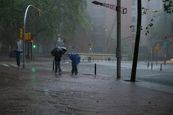 Varias personas caminan por la calle en el barrio de Canyelles-Nou Barris durante el episodio de lluvias de finales de septiembre. (Lorena Sopêna/Europa Press)