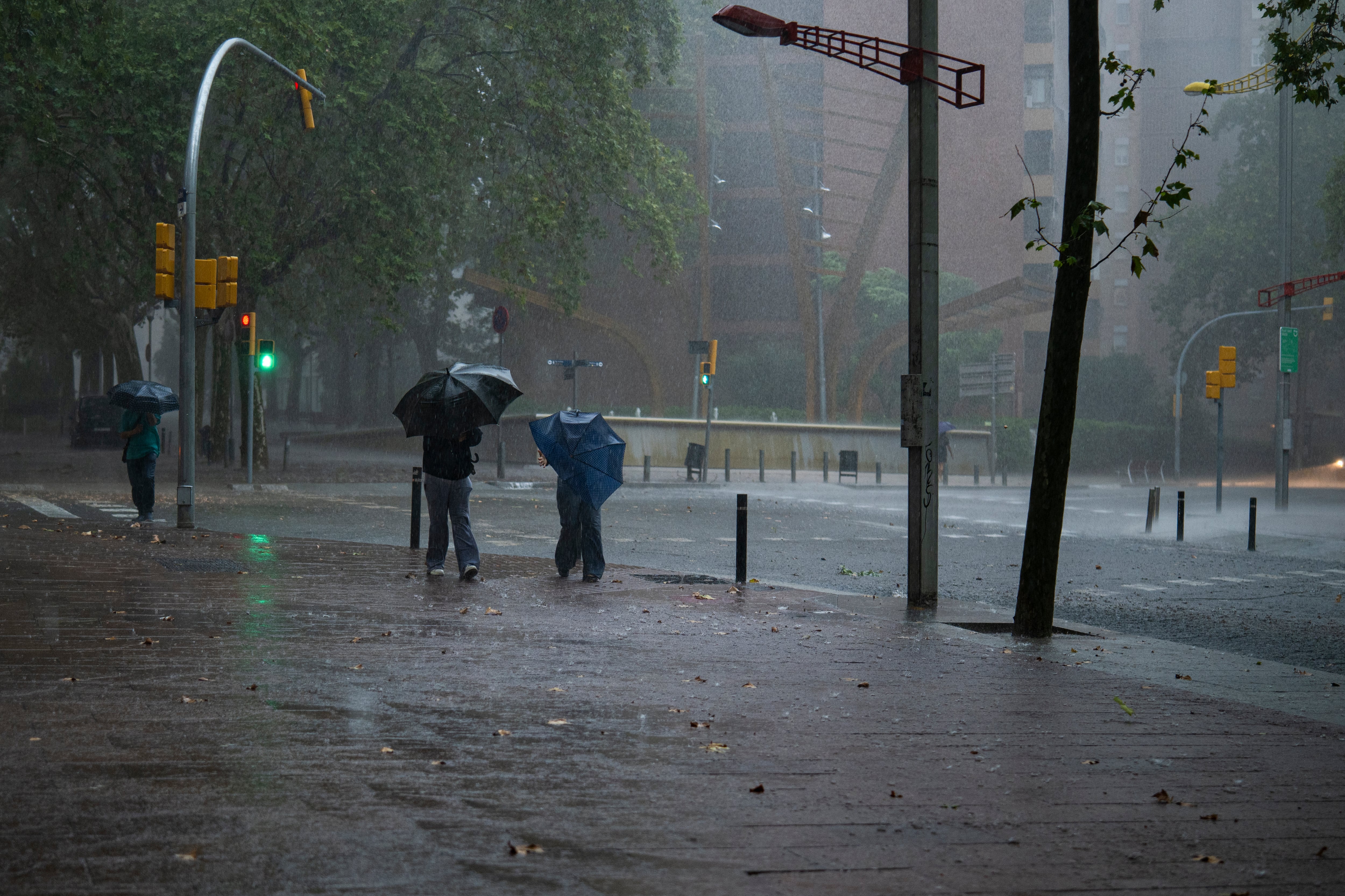 Varias personas caminan por la calle en el barrio de Canyelles-Nou Barris durante el episodio de lluvias de finales de septiembre. (Lorena Sopêna/Europa Press)