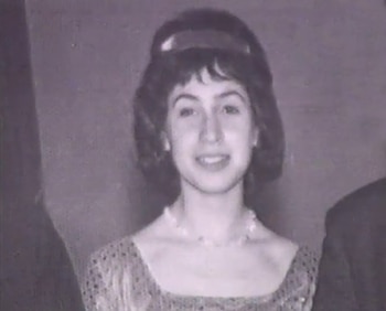 Retrato en blanco y negro de una mujer joven con cabello oscuro y flequillo, lleva una diadema, un collar de perlas y un vestido de escote cuadrado