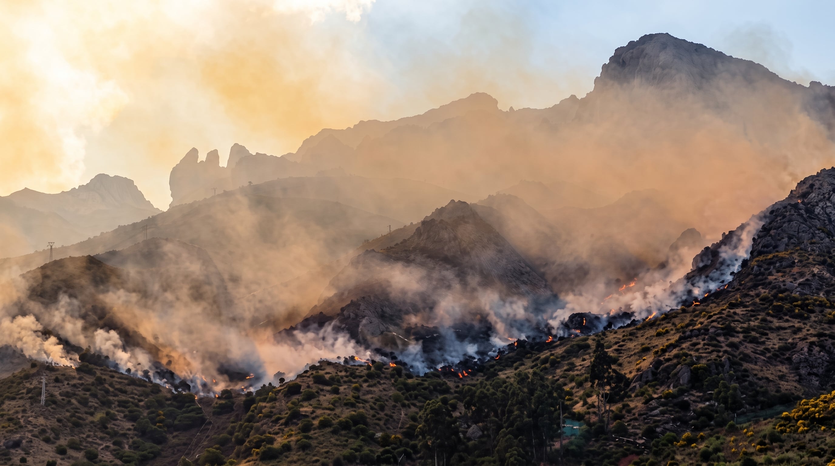 Un incendio forestal genera extensas columnas de humo y focos de fuego en las laderas de una cadena montañosa. (Imagen Ilustrativa Infobae)