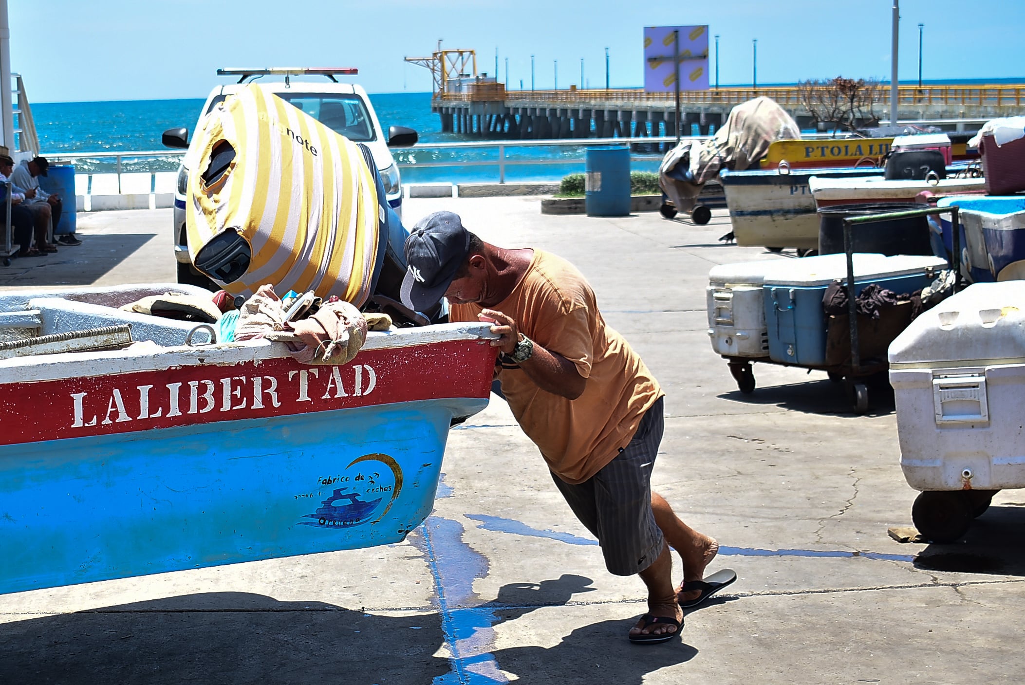 Noé Vásquez, un hombre que lleva 40 años dedicándose a la pesca, empuja su lancha en plena luz del medio día posterior a su jornada pesquera, su medio para ganarse la vida. (Infobae Centroamérica/Emerson Del Cid)