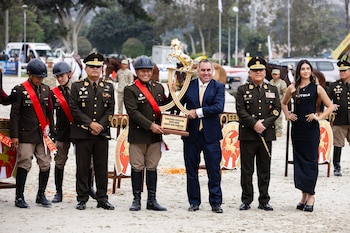 Militares, un civil y una mujer sostienen un trofeo dorado con un caballo en la cima. Al centro, una placa dice: Copa Junín Equipo Sub Campeón