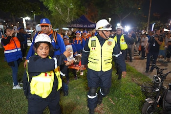 Rescatistas con cascos y chalecos reflectantes transportan a una persona en una camilla de noche en un parque