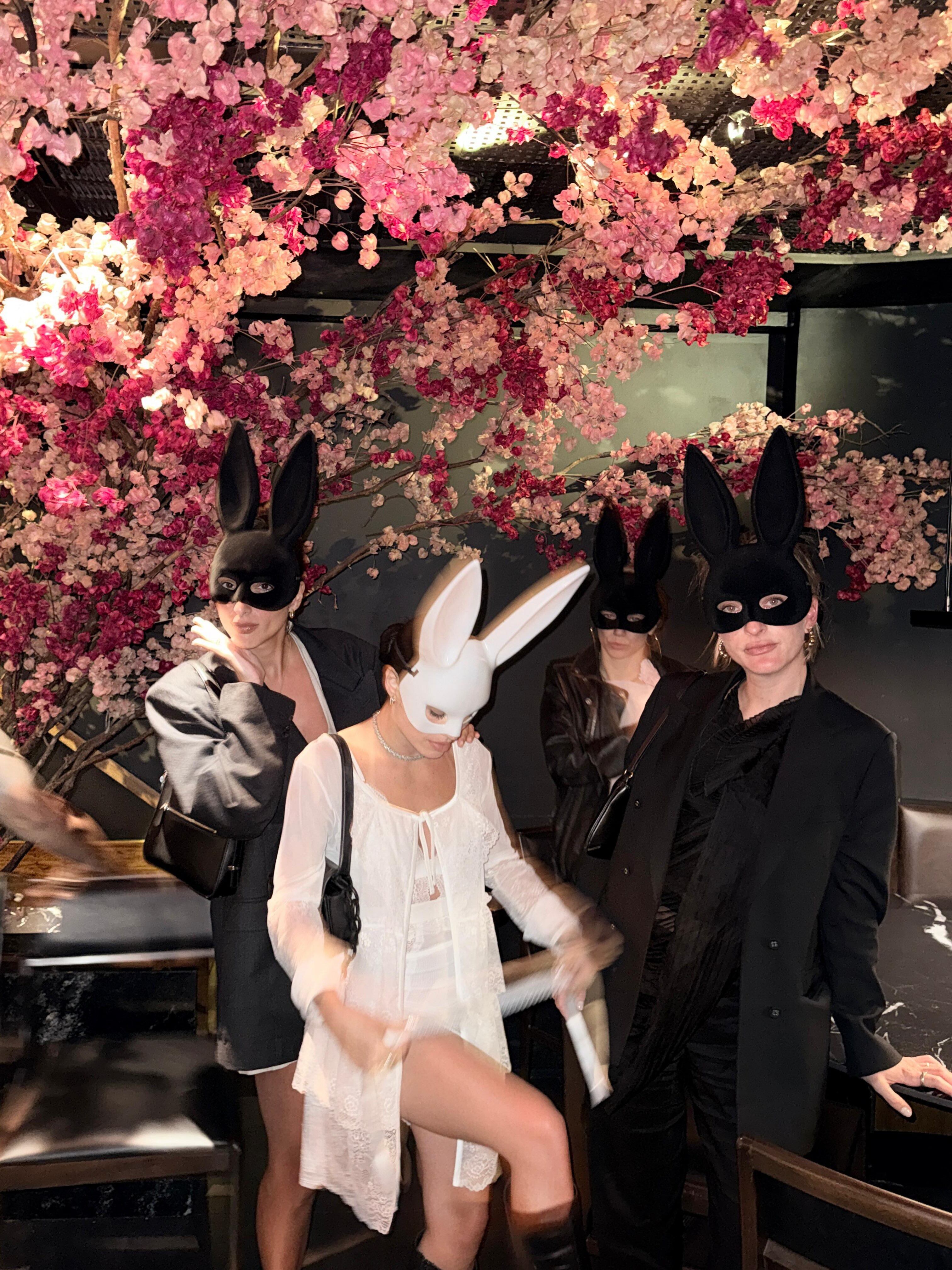 La novia diferenciada del grupo: Lali de blanco entre sus amigas de negro, todas con antifaces de conejo, en uno de los momentos de la noche central de la celebración en Río de Janeiro