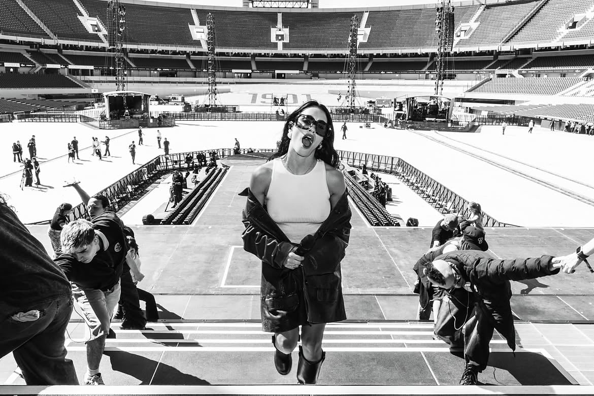 Lali sube las escaleras del escenario con actitud desafiante mientras su equipo trabaja a su alrededor en los últimos preparativos del show