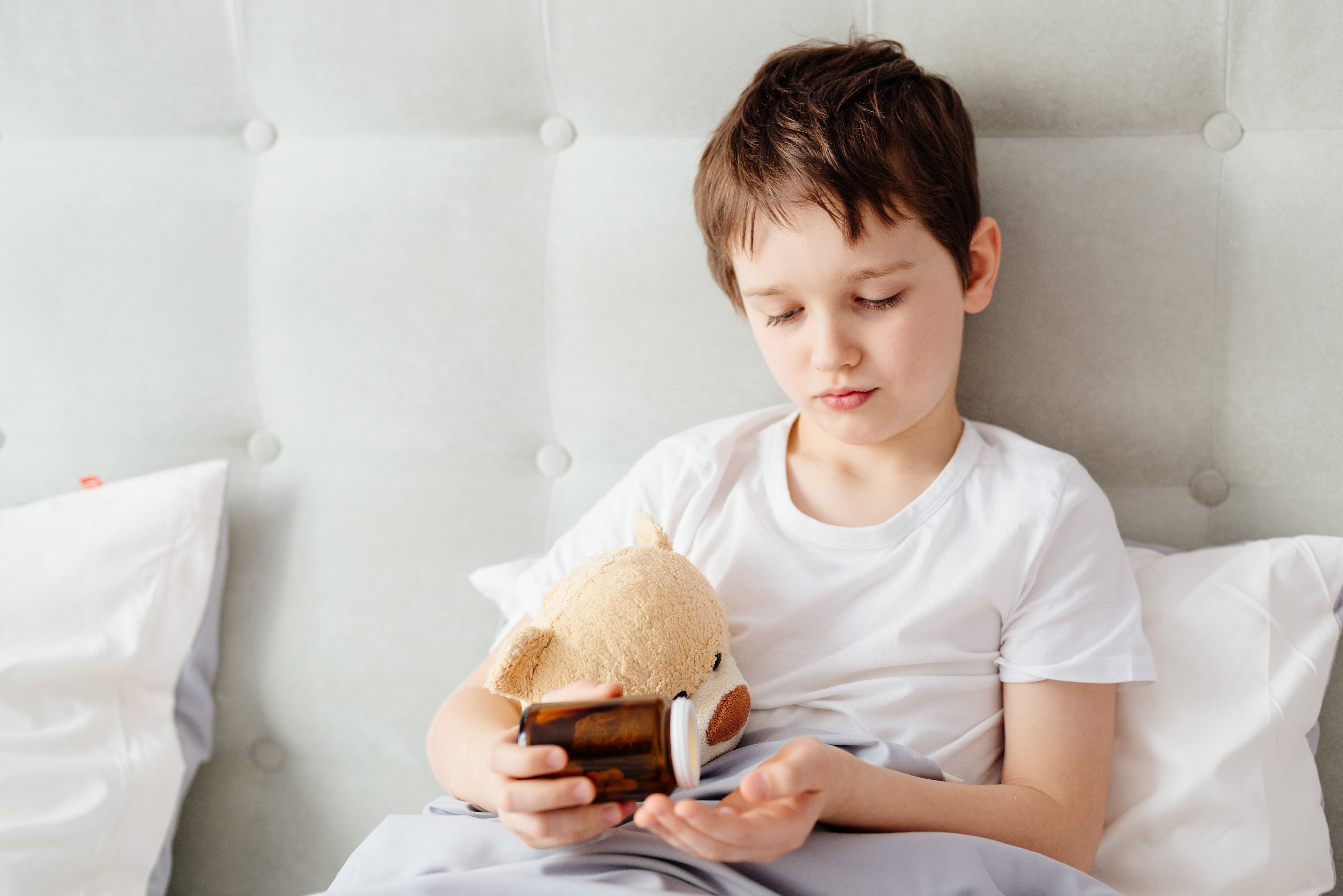 Un niño se toma las pastillas de un frasco (Adobe Stock)
