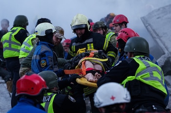 Los equipos de rescate trasladan en camilla a una mujer herida desde una casa gravemente dañada tras un ataque ruso contra un barrio residencial de Kiev, Ucrania, el jueves 14 de mayo de 2026 (AP/Evgeniy Maloletka)