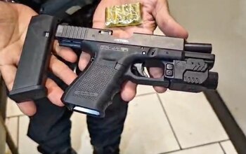 Una escopeta, un subfusil, dos pistolas, cargadores y diversos cartuchos y balas ordenados sobre una mesa de madera
