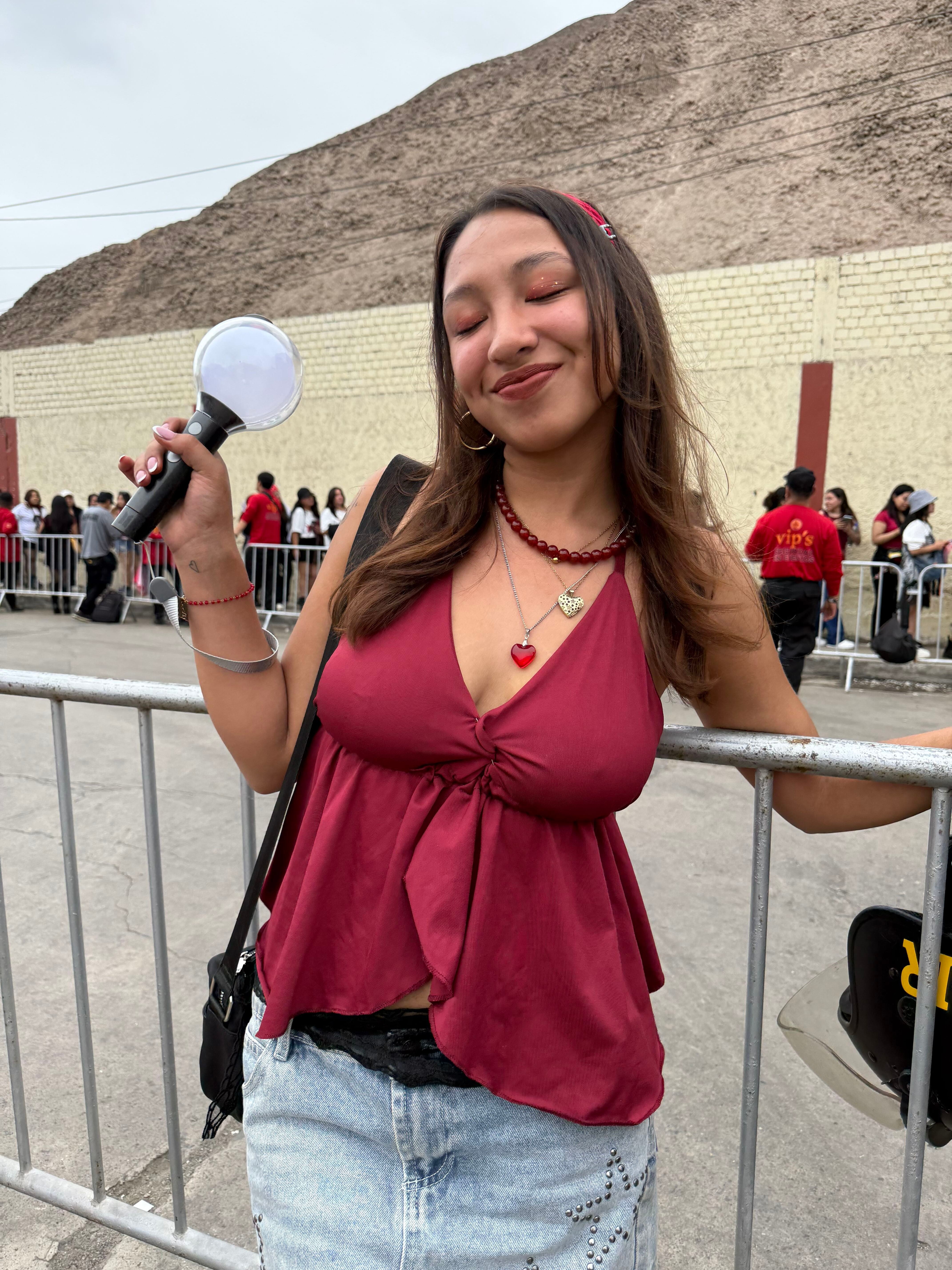 Una seguidora del grupo BTS sostiene un bastón de luz junto a las rejas de seguridad del Estadio San Marcos en Lima. (Paula Díaz)