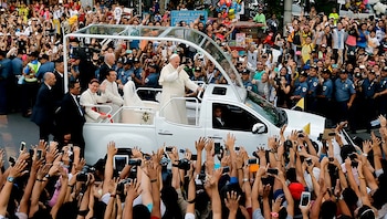 El papa Francisco, vestido de blanco, saluda rodeado de una multitud de personas que toman fotografías con sus teléfonos móviles