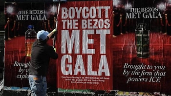 Pessoas por trás segurando um pôster vermelho com texto branco