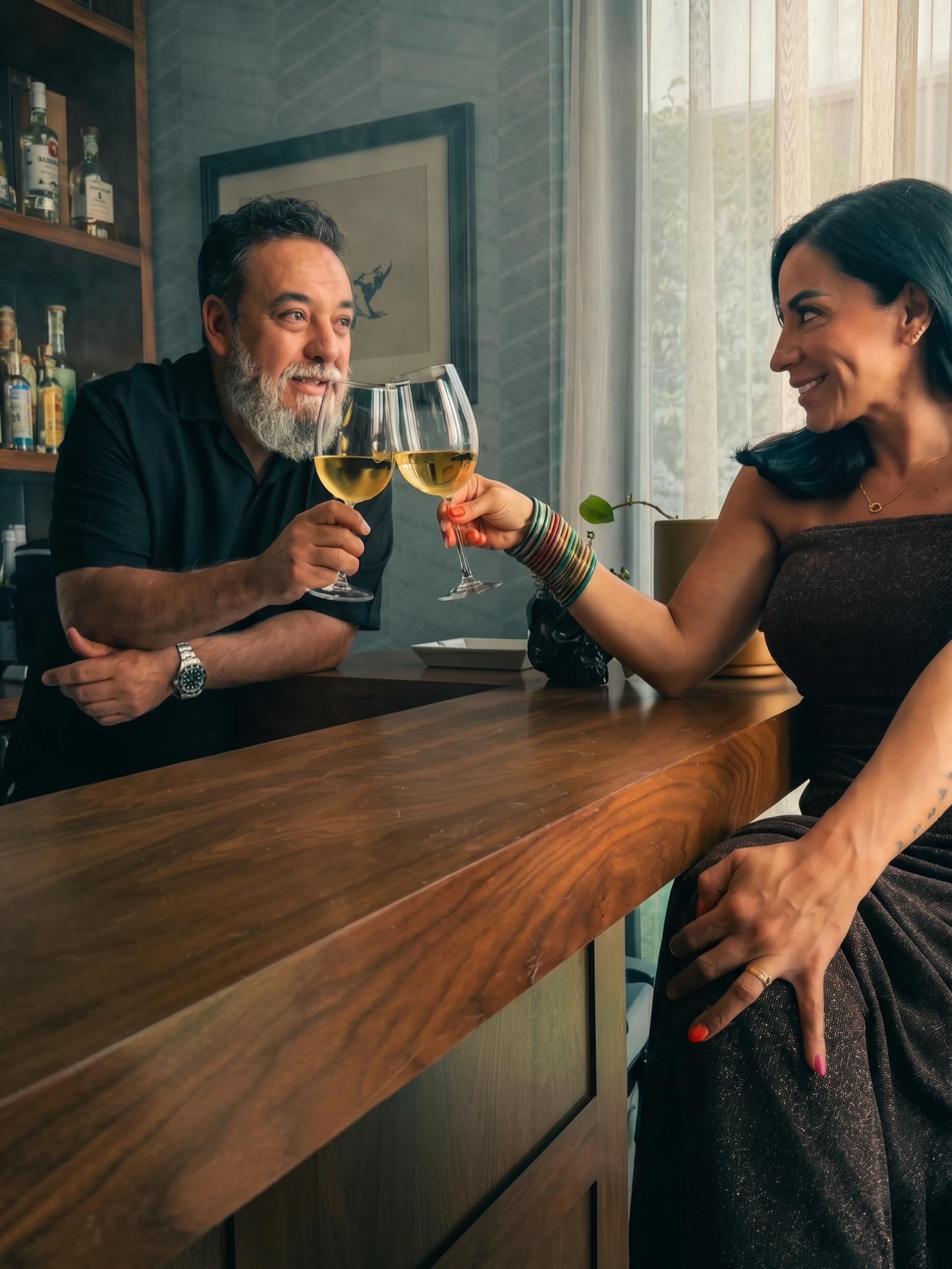Haydee Hofmann y su esposo Paco Ayala, bajista de la banda Molotov, brindan con copas de vino blanco frente a una barra de madera. (Instagram: Haydee Hofmann)