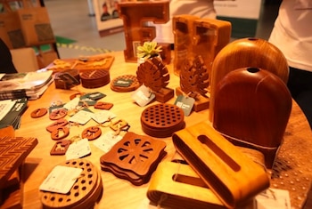Mesa con diversos objetos de madera tallada, como posavasos, llaveros, figuras decorativas, soportes y folletos informativos