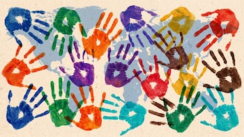 Múltiples huellas de manos de colores azul, verde, naranja, púrpura, rojo, amarillo, marrón y turquesa sobre el contorno de un mapa mundial sobre fondo beige