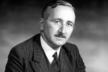 Fotografía en blanco y negro del economista Friedrich Hayek con anteojos, traje a rayas, camisa clara y corbata estampada.