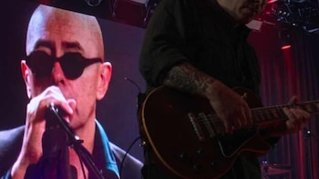 Imagen dividida: a la izquierda, Indio Solari en una pantalla con gafas de sol y micrófono; a la derecha, un guitarrista toca en un escenario con luces rojas