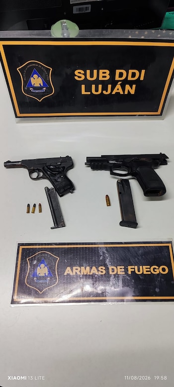 Dos pistolas, dos cargadores de munición, cuatro cartuchos y dos carteles de la Policía de Buenos Aires sobre una superficie blanca