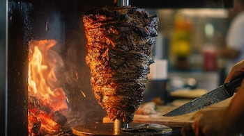Trompo de pastor negro, carne asada oscura, tacos mexicanos, tortillas de maíz, especias, antojito callejero, aroma intenso, piña fresca – (Imagen Ilustrativa Infobae)