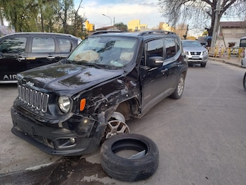 Camioneta Jeep Renegade negra con severos daños frontales, rueda delantera derecha faltante, neumático en el suelo, airbags desplegados. Otros vehículos