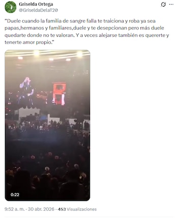 Christian Nodal canta en un escenario iluminado por luces brillantes, visto desde la perspectiva de una multitud de asistentes a un concierto