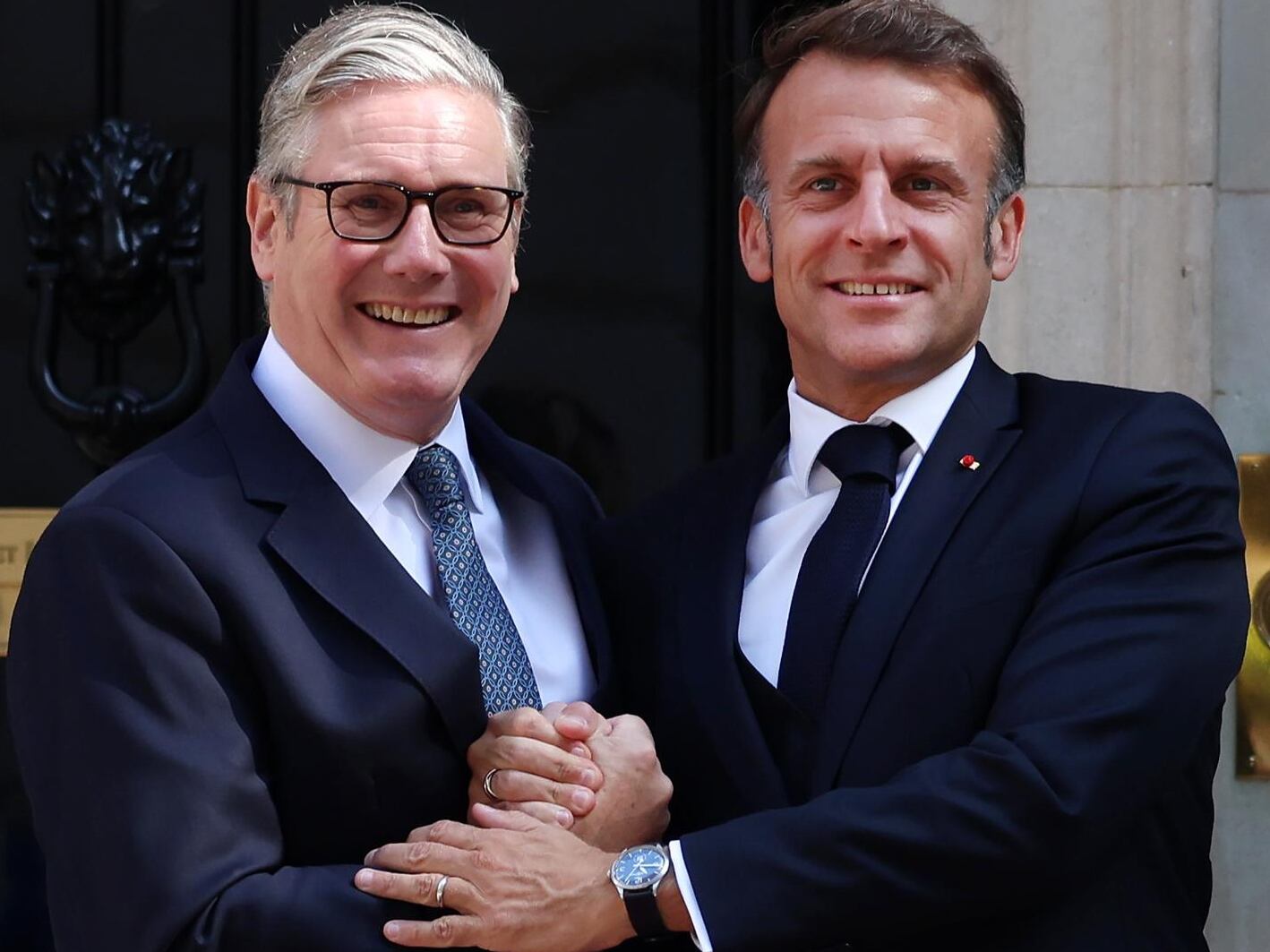 El primer ministro británico Keir Starmer (izquierda) y el presidente francés Emmanuel Macron (derecha) se abrazan antes de la cumbre entre el Reino Unido y Francia (EFE/EPA/ANDY RAIN / POOL)