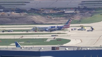 Avión comercial de American Airlines en la pista de un aeropuerto junto a vehículos de auxilio y personas reunidas en el suelo