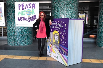 Una mujer con gafas de sol posa junto a un libro gigante y un cartel con el texto Pensá mejor usá el subte