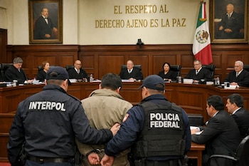 Dos agentes, uno de Interpol y otro de la Policía Federal, escoltan a un hombre esposado frente a los jueces de la SCJN en una sala de audiencias.