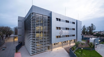 Vista exterior de un edificio hospitalario moderno de color gris con ventanas grandes y celosías horizontales, identificado como Centro Integral de Salud La Banda