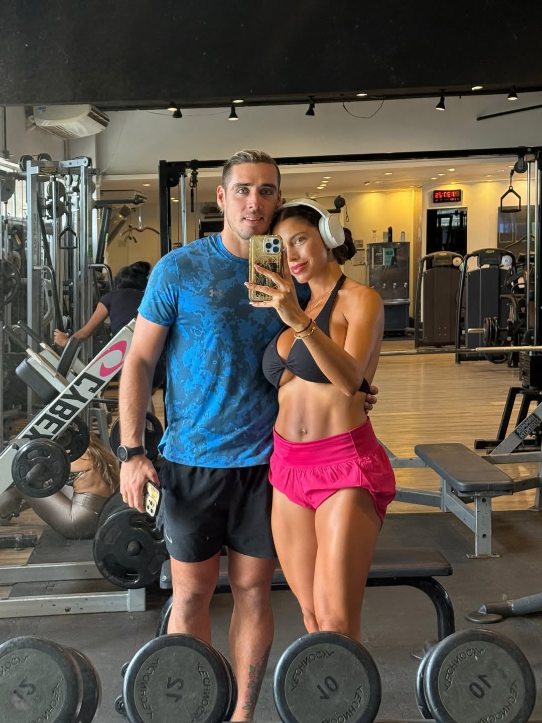 El futbolista Claudio Spinelli y la modelo Cielo López se toman una fotografía frente al espejo dentro de un gimnasio.