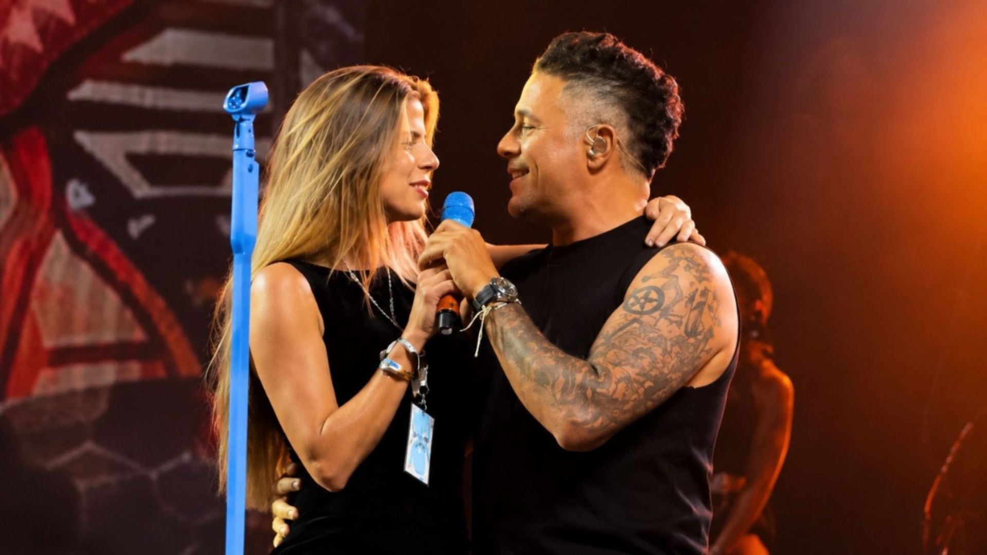 El cantante español Alejandro Sanz y la actriz peruana Stephanie Cayo interpretan una canción sobre el escenario durante un concierto.