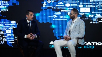 Dos hombres sentados en sillas frente a un fondo digital azul con un mapamundi de píxeles y logotipos de diversas marcas