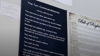 Primer plano de dos pósteres en una pared blanca: uno con Los Diez Mandamientos en texto blanco sobre fondo negro y otro con la Declaración de Derechos de EE. UU