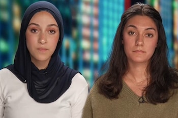 Dos mujeres jóvenes miran a la cámara; una lleva un hiyab oscuro y la otra tiene el cabello suelto y viste un suéter verde
