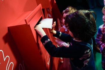 Niños entregando sus cartas a los Reyes Magos en un buzón habilitado por la Comunidad de Madrid